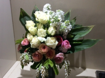 peaches and cream - A beautiful selection of seasonal flowers in peach and cream tones accompanied with lush foliage arranged in a glass vase .